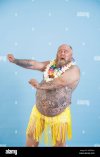 emotional-man-with-overweight-in-decorative-grass-skirt-adances-on-light-blue-background-2GFFEAH.jpg