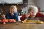 happy-brothers-holding-knives-at-table-with-vegetables-in-kitchen.jpg