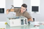 26769577-attractive-angry-computer-engineer-destroying-computer-with-hammer-in-bright-office.jpg